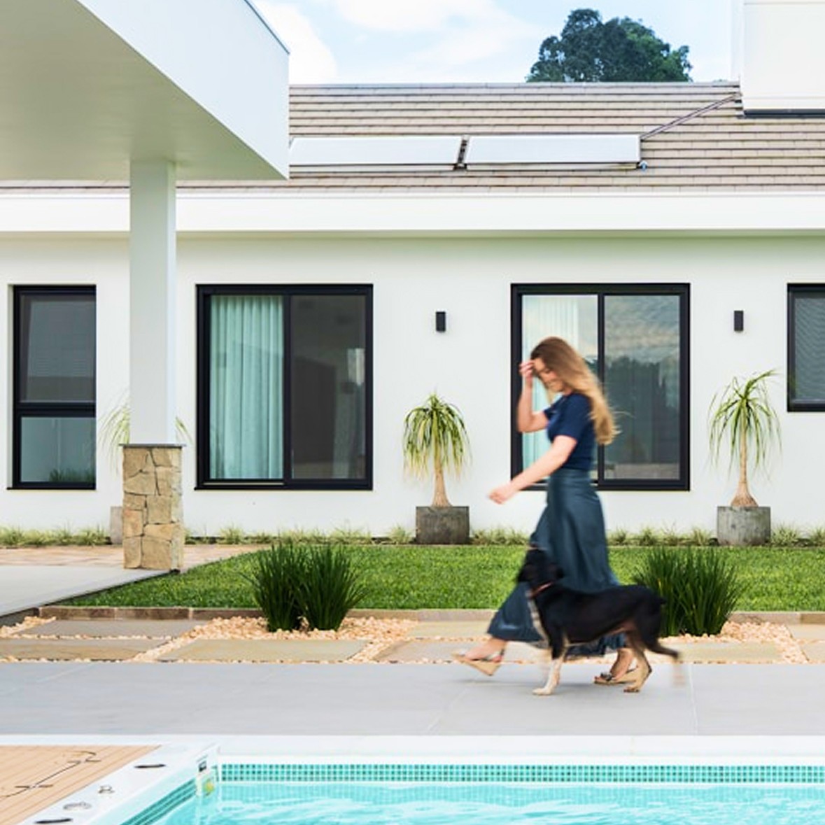 A homeowner walking with a dog in front of a modern house